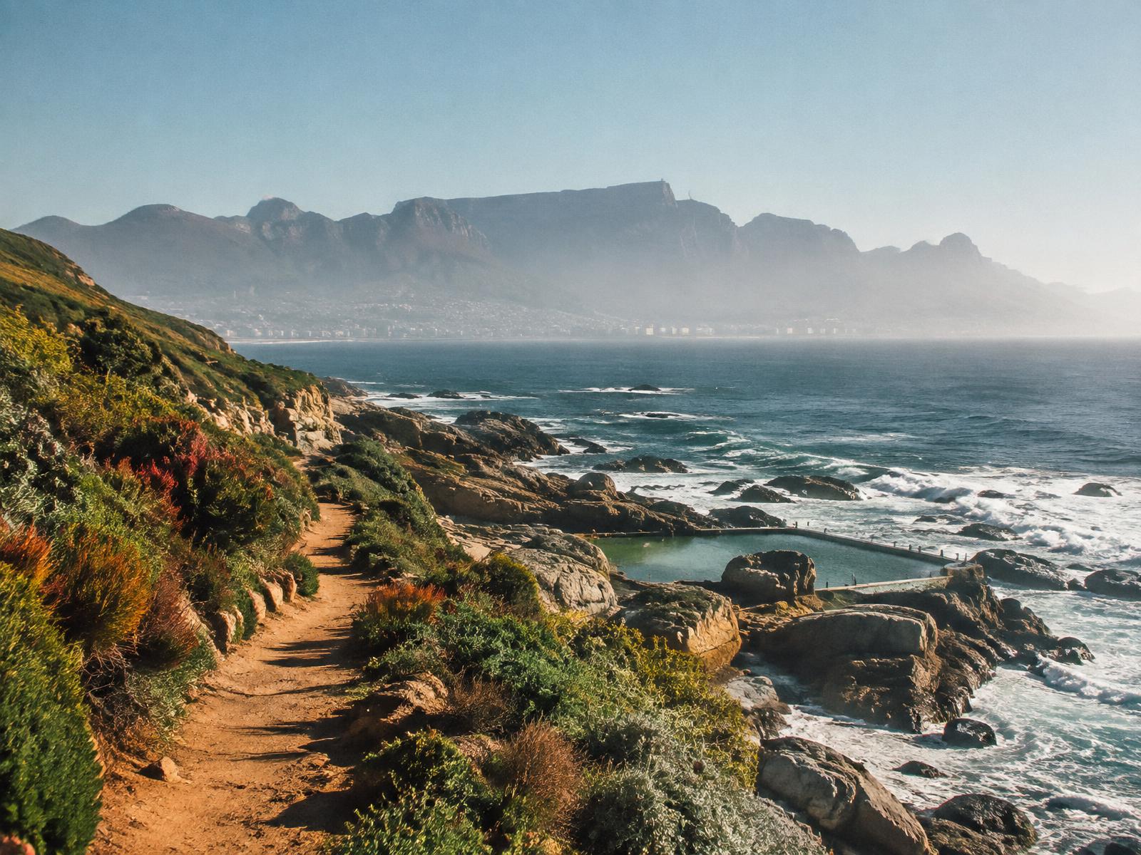 Coastal path with fynbos, tidal pool and Table Mountain in the haze