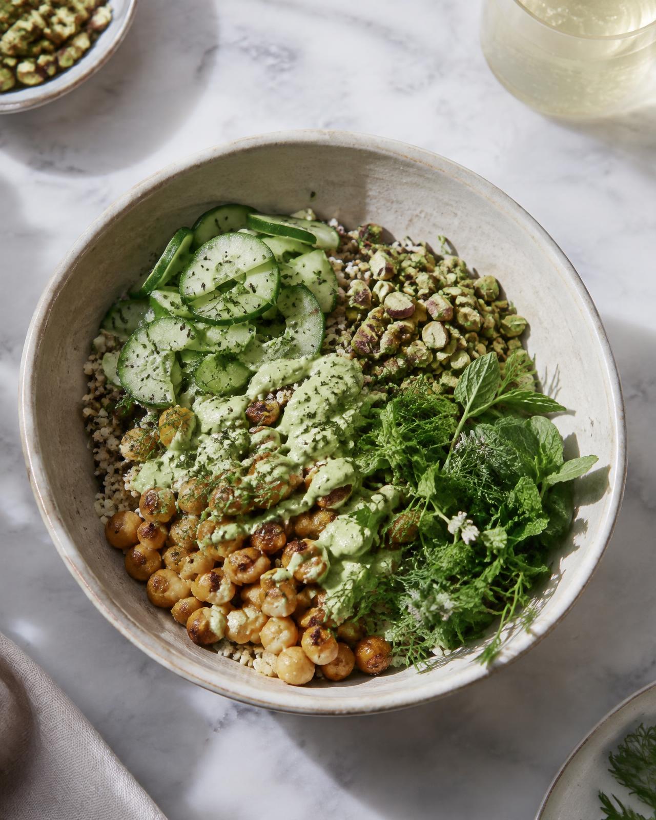Grain bowl with green tahini sauce, cucumber, crisp chickpeas, pistachio and herbs