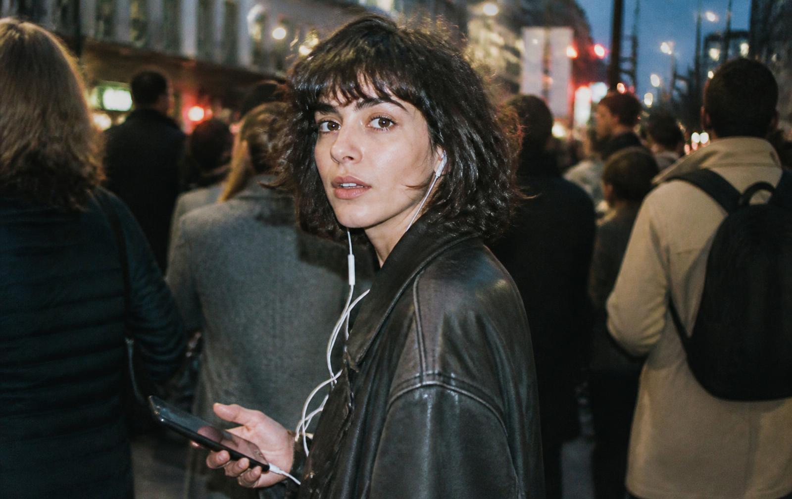 A woman looking away from a phone in a quiet, strongly lit room