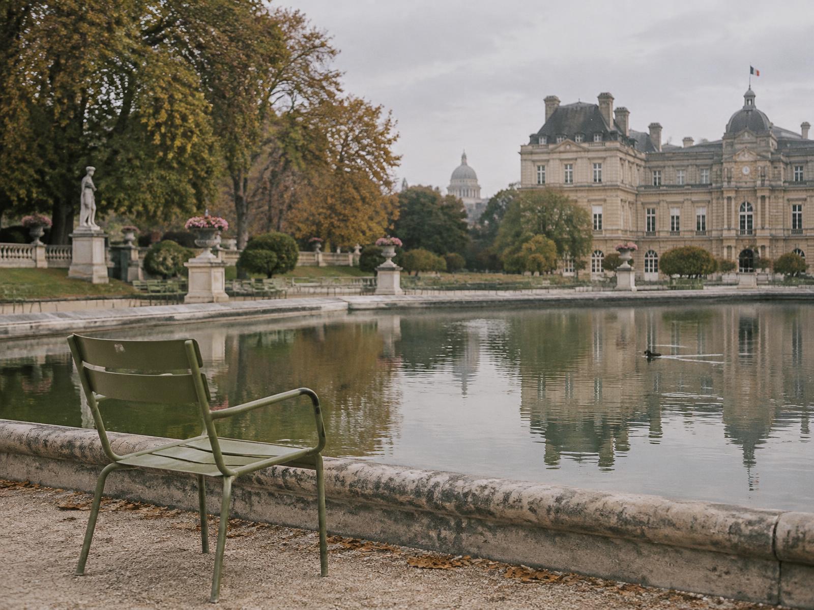 A green chair beside the water in Jardin du Luxembourg on an overcast morning